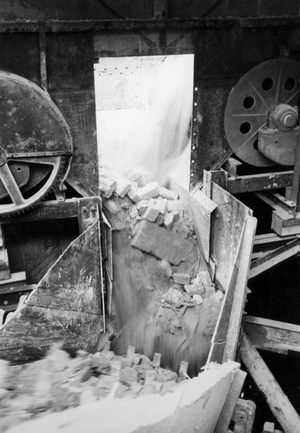 An einer Trümmerverwertungsstelle fällt der Schutt in eine Sortiermaschine.