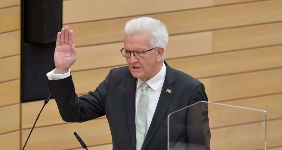 Vereidigung Winfried Kretschmann. Man sieht Kretschmann vor holzvertäfeltem Hintergrund wie er den rechten Arm zur Vereidigung hebt.